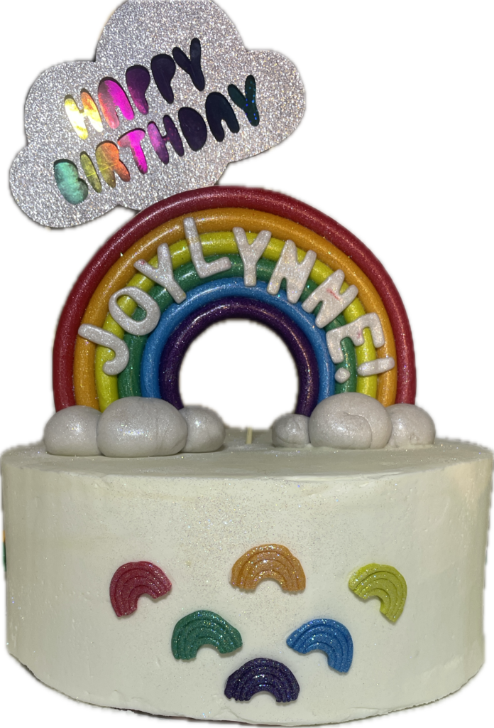 White cake decorated with a large fondant rainbow and mini fondant rainbows